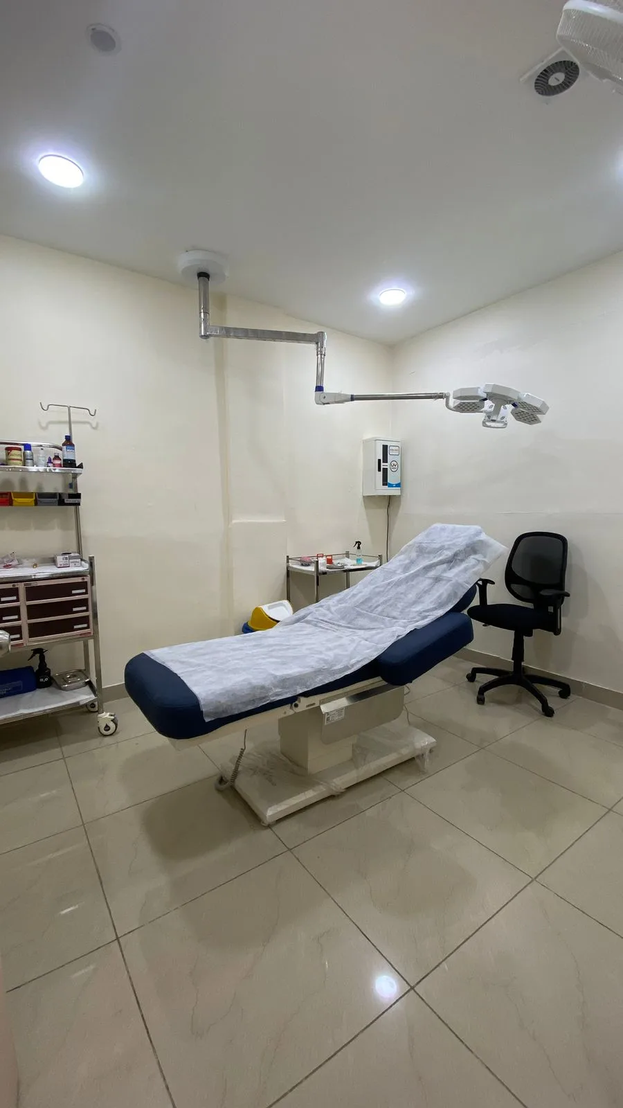 Surgical room with dual shadowless operating lights, blue procedure bed and instrument trolley